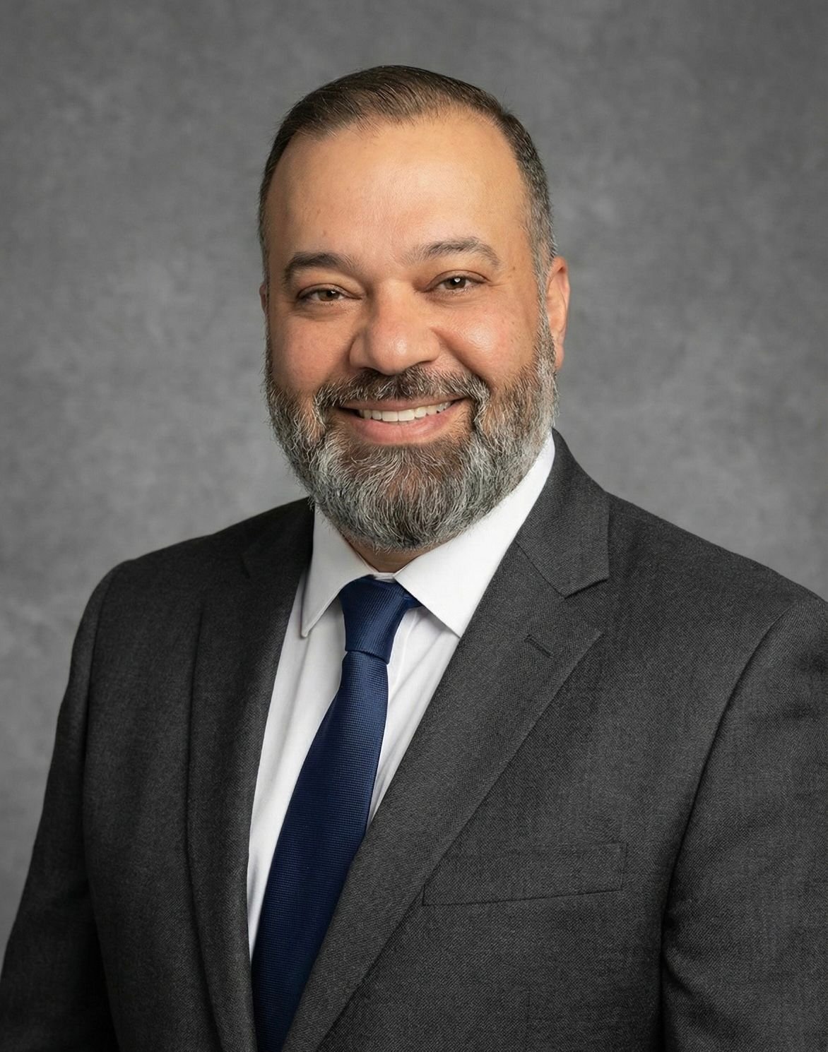Dr. Sam Sammane, professional headshot in a charcoal suit